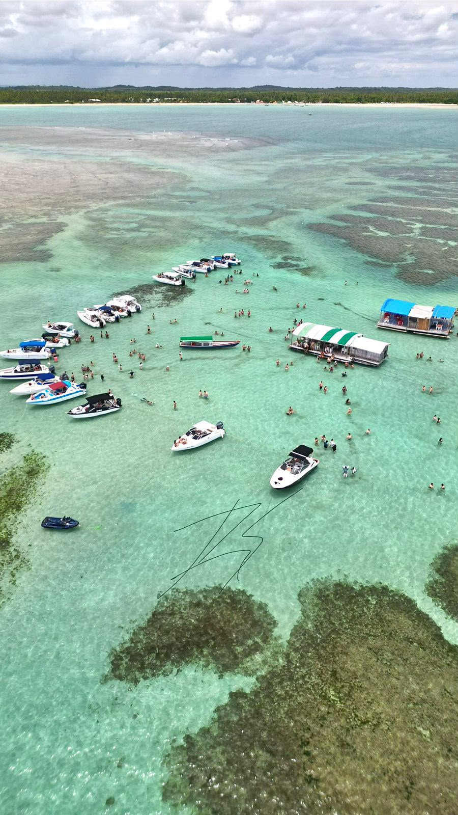 Vista aérea de lanchas e banhistas nas piscinas naturais de águas turquesa